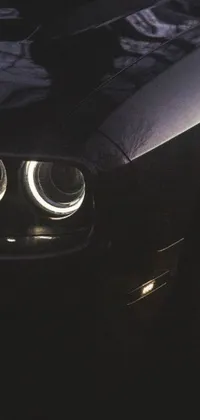 This Phone Live Wallpaper features a high-quality image of the headlight of a glossy black car