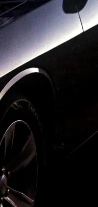 Looking for a striking phone live wallpaper? Check out this black car parked on the side of the road, featuring graphic detail and a rim-light that is sure to impress