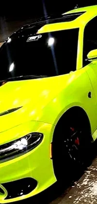 This phone live wallpaper captures a yellow Dodge Charger parked in a dimly lit parking lot with a vibrant background of Lyco Art neon green lava streets