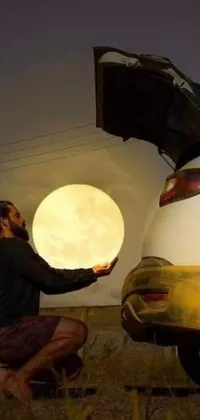 This phone live wallpaper showcases a hyperrealistic painting of a man admiring a car beneath a large glowing moon