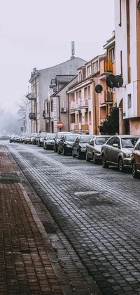 This live wallpaper depicts a quiet street in a quaint village where parked cars are seen next to tall buildings