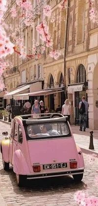 This phone live wallpaper captures the essence of Parisian charm, with a pink car driving down a cobblestone street and beautiful girls walking on the sidewalk