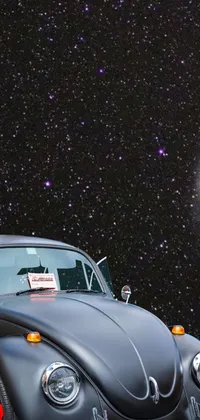 This live phone wallpaper displays a classic black Volkswagen Beetle parked in front of a breathtaking starry night sky in cosmic purple