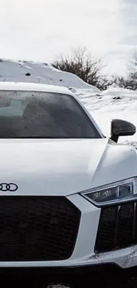 This phone live wallpaper depicts a man standing next to a white sports car in the snow