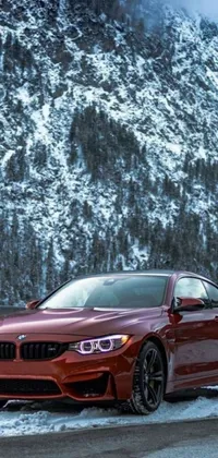 Get ready to hit the road with this stunning live wallpaper on your phone! A red BMW car can be observed driving through snowy terrain surrounded by mountains in this wallpaper