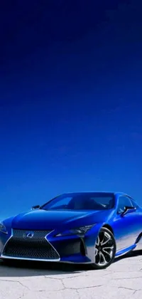 This live phone wallpaper features a blue sports car parked in the desert, set against a dark blue sky and golden yellow horizon