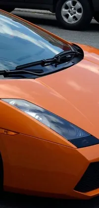 This phone live wallpaper showcases an orange sports car parked in a busy parking lot