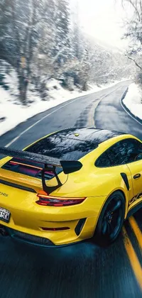 This mesmerizing phone live wallpaper showcases a stunning yellow sports car driving down a snow-filled road