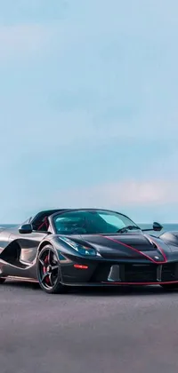 This phone live wallpaper showcases a black Ferrari F50 parked in front of an ocean backdrop