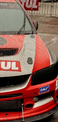 This live phone wallpaper showcases a stunning red and white rally car parked in a lot
