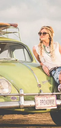 Looking for a phone live wallpaper that captures the spirit of adventure and freedom? Check out this promotional image featuring a blonde woman sitting on top of a green car with a backdrop of a scenic road, possibly Route 66