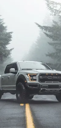 Impress your friends with this stunning live wallpaper featuring a Ford F-150 Raptor pickup truck driving along a foggy road, set against a beautiful forest backdrop