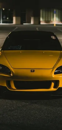 This stylish live wallpaper features a vibrant yellow sports car parked on a city street at night
