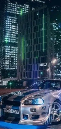 The Nōami Live Wallpaper depicts a Nissan GTR R 3 4 parked on a bustling city street at night, illuminated by vibrant neon lights