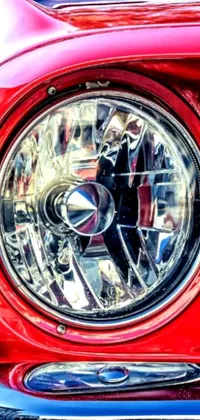 This live wallpaper for phones features a brilliant close-up of a ruby-red car's headlight rendered in hyper-realistic detail by a skilled artist