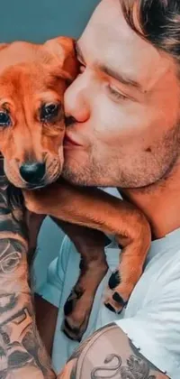 This mobile live wallpaper showcases a rugged man cradling a small dog