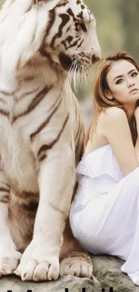 This stunning phone live wallpaper portrays a woman sitting on a rock with a white tiger in a lush forest setting