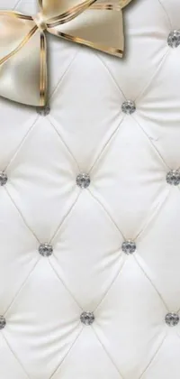 Enhance your phone with this luxurious and elegant live wallpaper featuring a white quilted background with a gold bow, digital rendering, art deco style, adorned with sparkling gems, leather, silver, ivory and gold accents