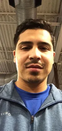 This phone live wallpaper captures a close-up view of an athletic person wearing a blue shirt in a gym, featuring a distinctive Mexican mustache