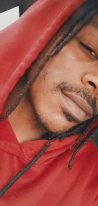 This phone wallpaper showcases a captivating close-up of a man with dreadlocks sitting in a car while wearing a red hoodie