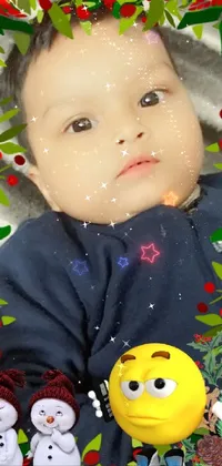 This live phone wallpaper features a heartwarming scene of a happy baby laying on a soft blanket next to a colorful Christmas ornament