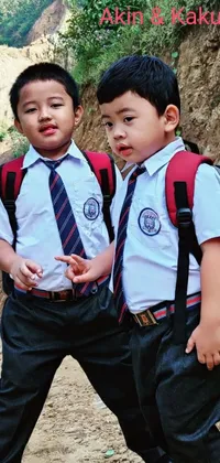 This charming live wallpaper depicts two young boys wearing academic uniforms, standing side by side in front of a picturesque backdrop of mountains in Nepal