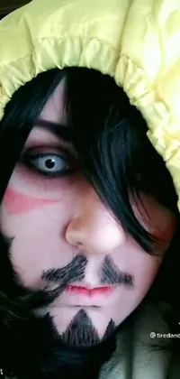 This phone live wallpaper showcases a close-up of a person with a hood, wearing yellow makeup