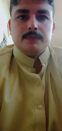 This phone wallpaper features a close-up of a professional attire with a thin mustache wearing yellow clothes, shot using a webcam