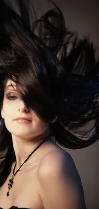 This phone live wallpaper depicts a breathtakingly beautiful woman with long, black hair being blown by the wind
