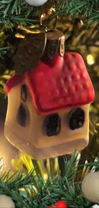 This Christmas-themed live wallpaper showcases a small and intricately designed house ornament hanging from a holiday tree