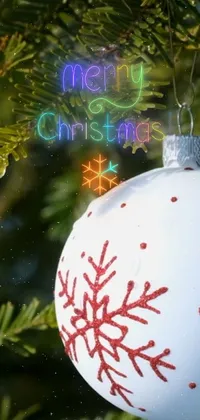 This live wallpaper for phones showcases a close-up of a winter-themed ornament hanging on a Christmas tree