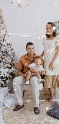 This phone live wallpaper features a heartwarming portrait of a couple holding their little one in front of a festive Christmas tree