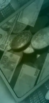 This live phone wallpaper features a pile of money on a table