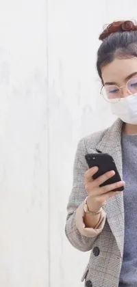 This live wallpaper features a woman wearing a face mask, looking at her phone while standing amidst a high-tech environment
