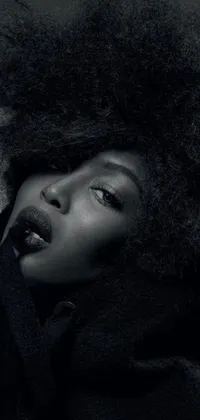 This phone wallpaper features a black and white photograph of a beautiful woman with an afro hairstyle, wrapped in a black scarf and wearing a sleek dark fur coat