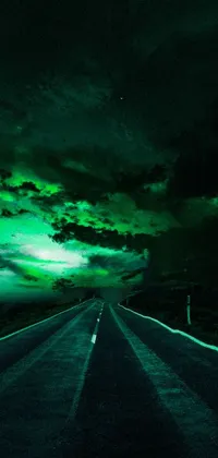 This beautiful live phone wallpaper depicts a long road leading to a distant horizon against a green sky with night clouds in the background