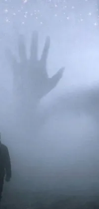 This phone live wallpaper features a surreal and haunting scene of a hand-faced person walking deep into a digital reality amid dense fog