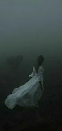 This phone live wallpaper depicts a woman dressed in white walking through a foggy field with an ox in the background