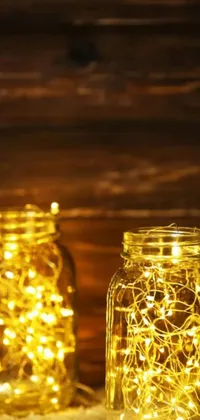 This live phone wallpaper features mason jars filled with fairy lights resting on a wooden table with a framed picture above