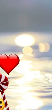 This mobile live wallpaper boasts a heart-shaped lollipop with a stick protruding from it