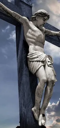 This live phone wallpaper features a stunning statue of Jesus on the cross against a cloudy sky