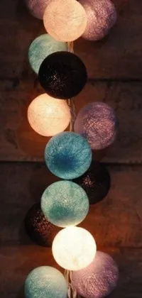 This live phone wallpaper features a beautiful string of light bulbs hanging from a wooden wall, set against a light and space-themed background in black and aqua colors
