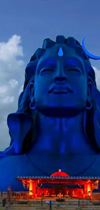 This live wallpaper features an impressive blue statue set against a lush green field