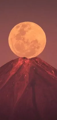 This live phone wallpaper showcases a breathtaking digital art image of a full moon rising over a towering mountain in a dormant volcano
