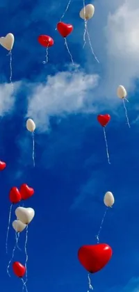 Looking for a lively and vibrant wallpaper for your phone? Check out this stunning live wallpaper featuring red and white balloons floating gently in a clear blue sky