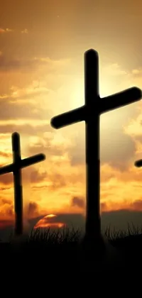 This phone live wallpaper showcases three crosses situated on a hill against a sunset in the backdrop