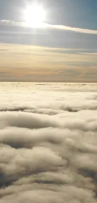 This phone live wallpaper features a stunning scene of a plane flying high above a blanket of fog and golden clouds