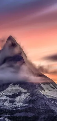 This live wallpaper showcases a majestic snow-covered mountain landscape with clouds in the background as the setting sun casts a warm glow over the area