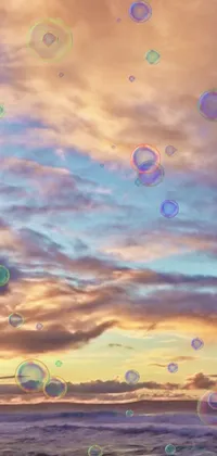 This live phone wallpaper features soap bubbles floating amidst a stunning sunset and cloudscape