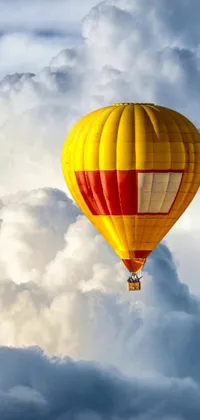 This phone live wallpaper features a brilliant hot air balloon in yellow and red, gracefully soaring across a cloudy sky